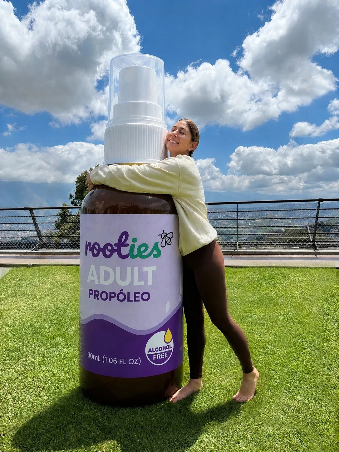 Mujer abrazando una botella gigante de Rooties Adult sobre el césped