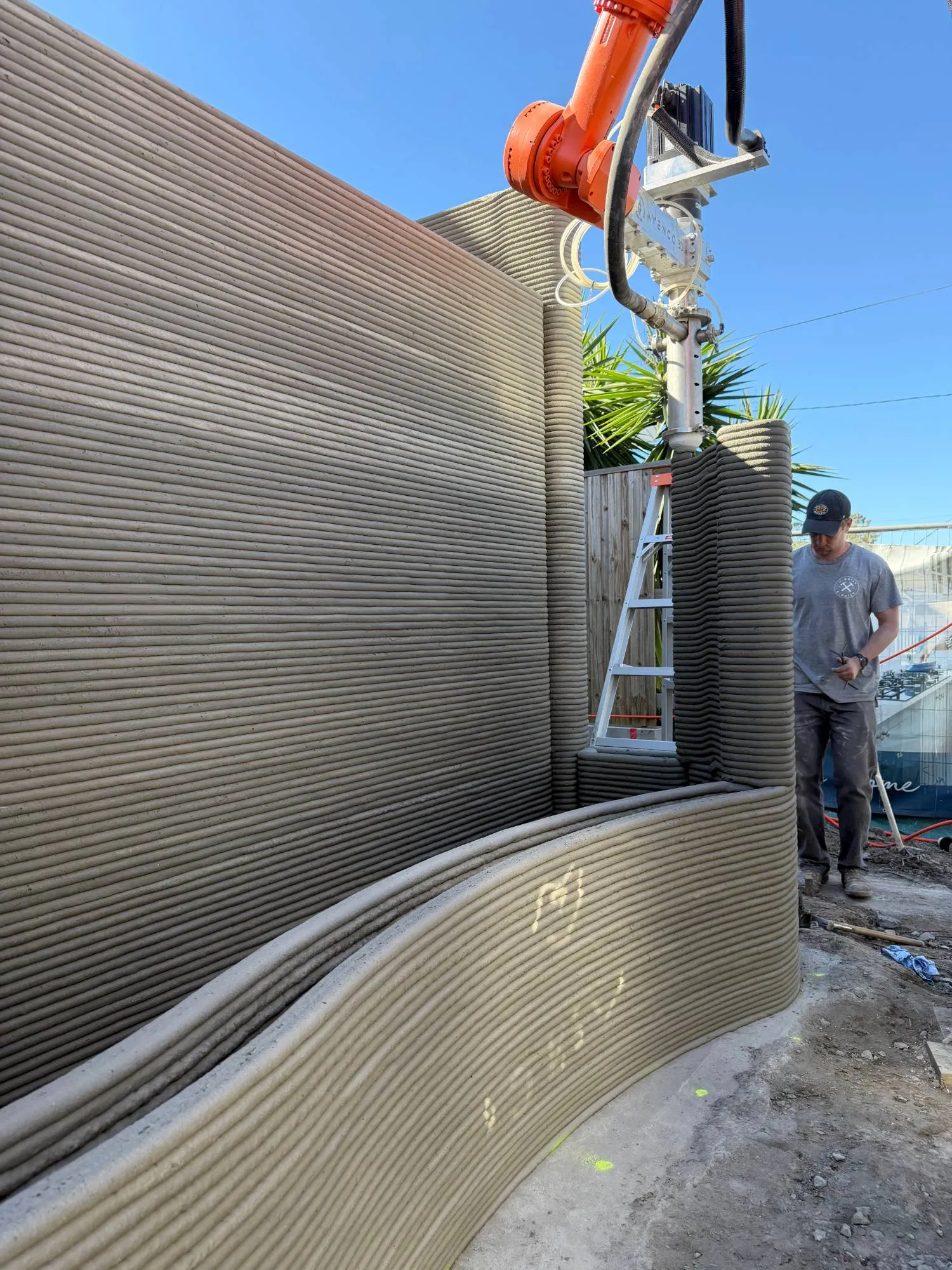 Brazo robótico imprimiendo un muro curvo en obra